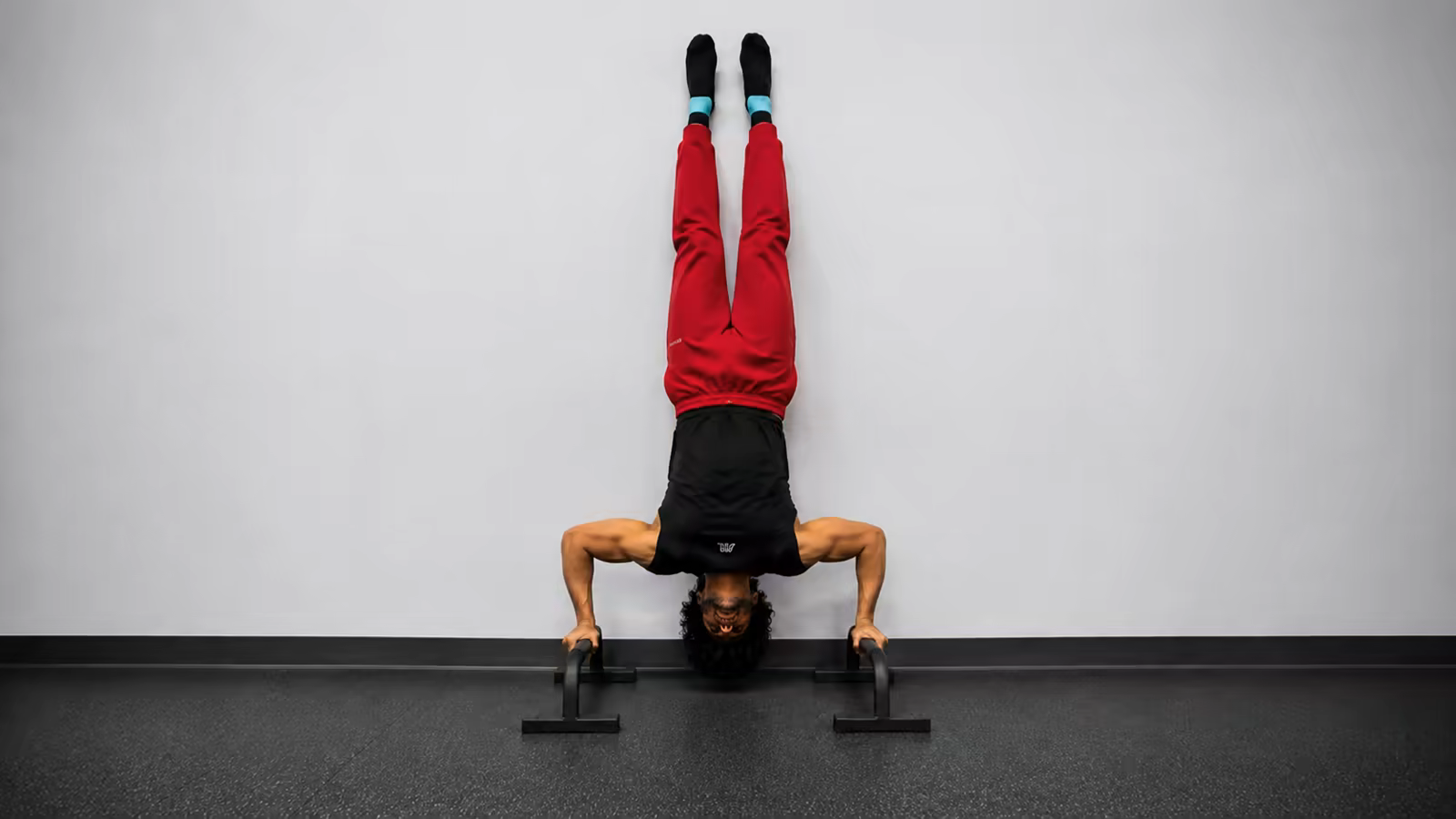 The wall shrug drill teaches your shoulders the active position that holds a freestanding handstand together.